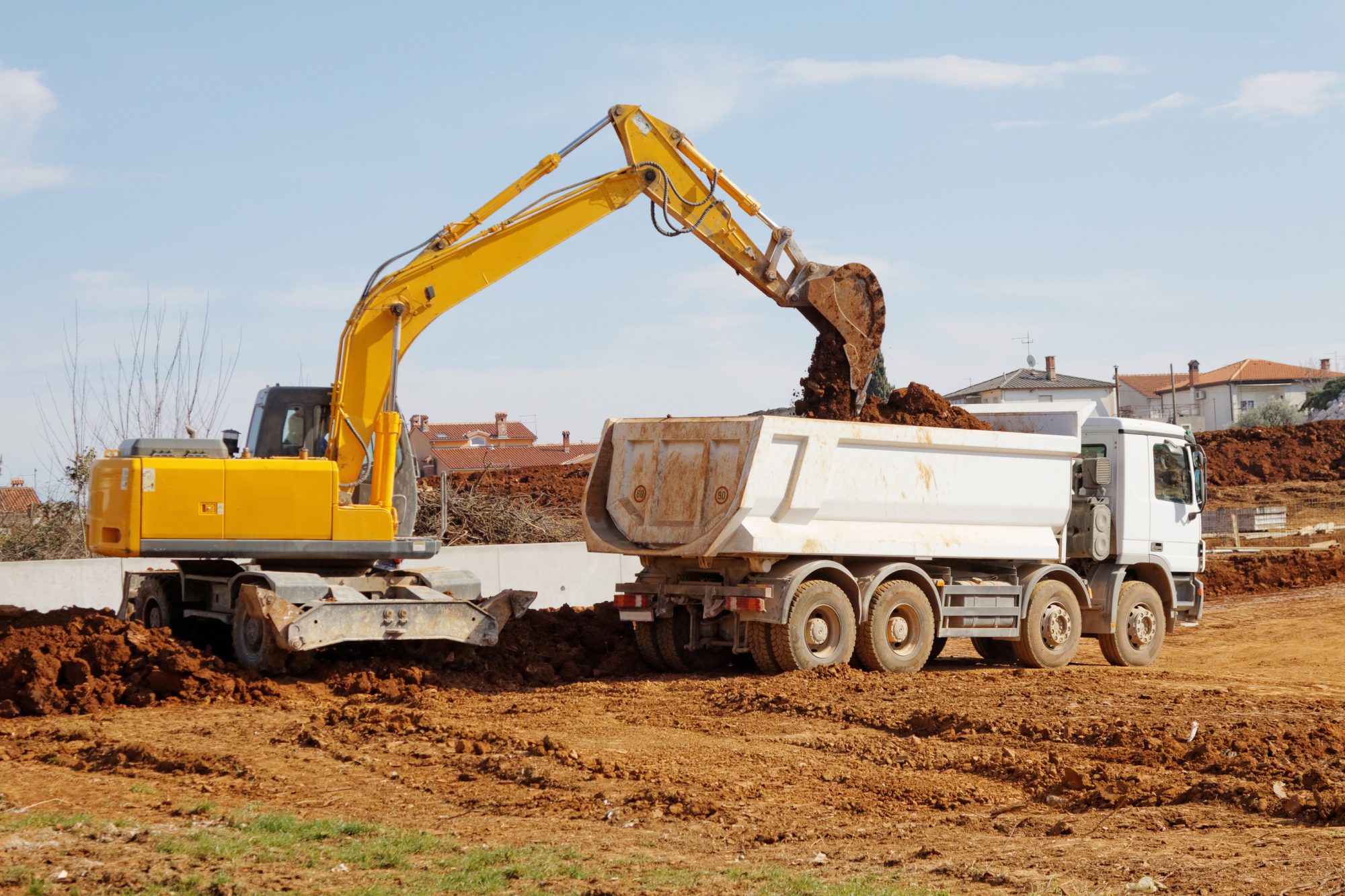 Industrial excavator loading tipper truck on construction